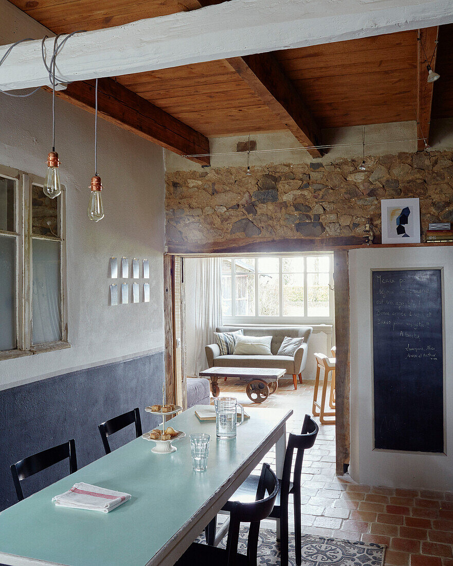 Tortenständer auf einem Tisch mit Tafel und freiliegendem Stein in einem bretonischen Landhaus in Frankreich