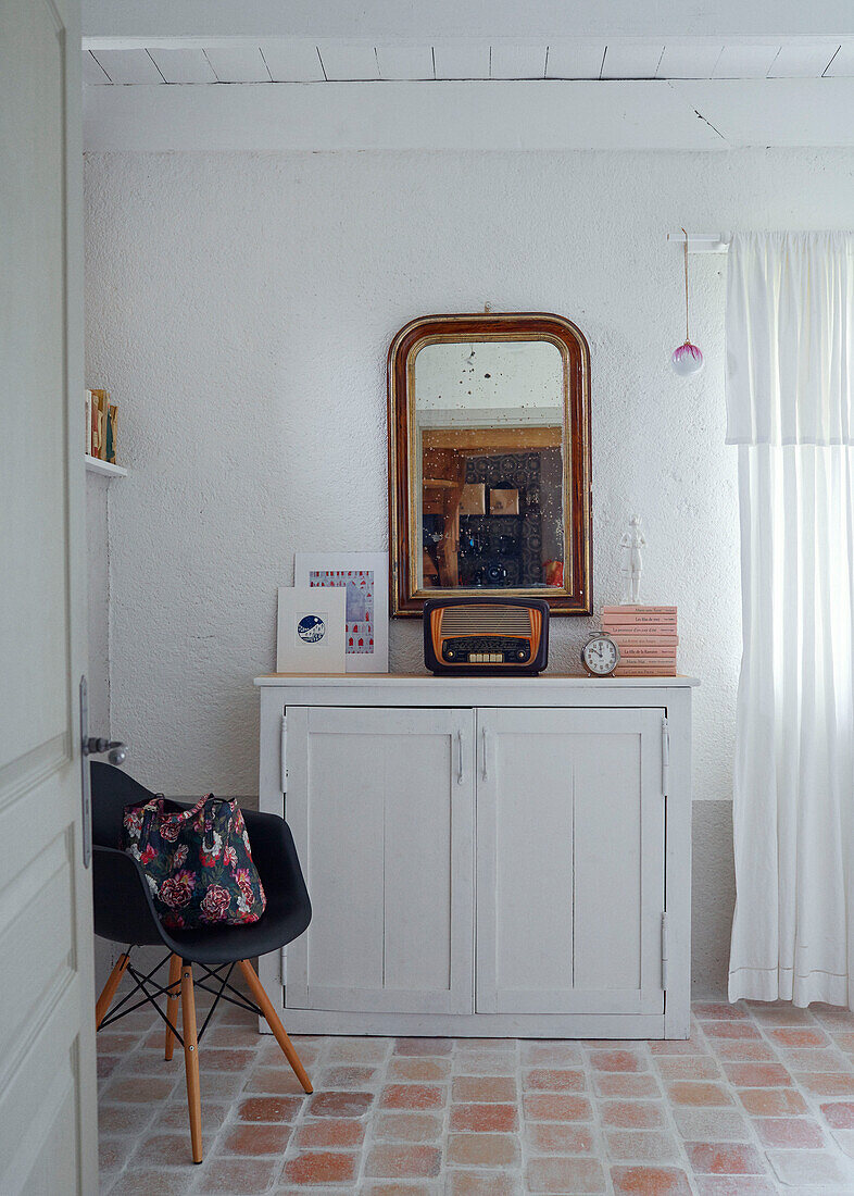 Mirror and radio on sideboard with DSW chair in Brittany cottage, France