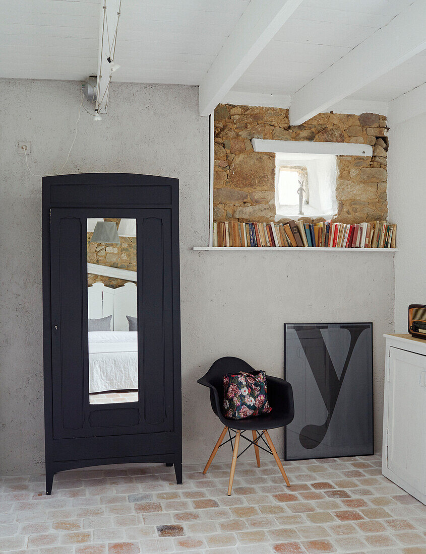 Schwarzer Stuhl und Schrank mit Bücherregal und gerahmtem Buchstaben 'y' in bretonischem Landhaus in Frankreich