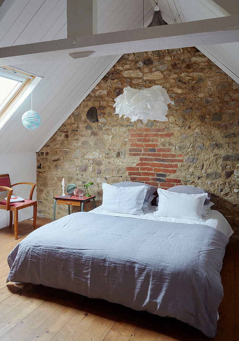 Double bed in exposed stone attic conversion of Brittany cottage, France