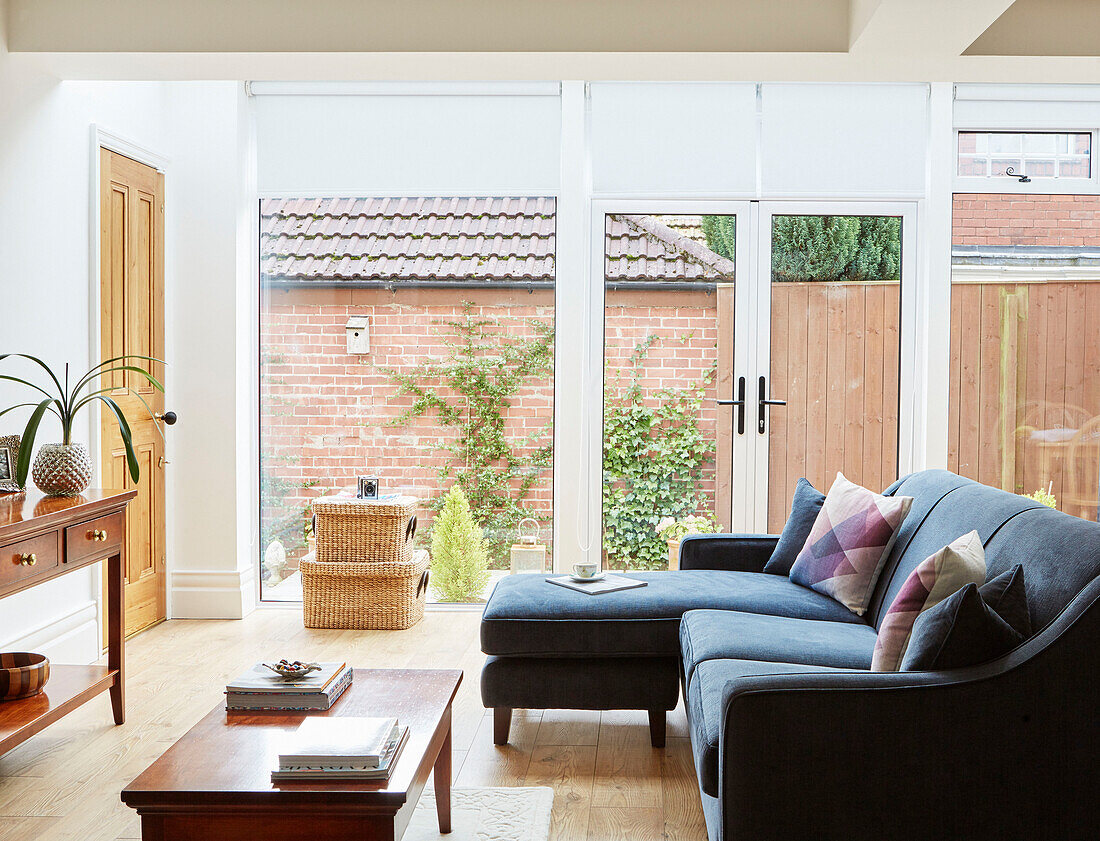 Corner sofa and baskets with wooden table and glass patio doors in Durham home, England, UK