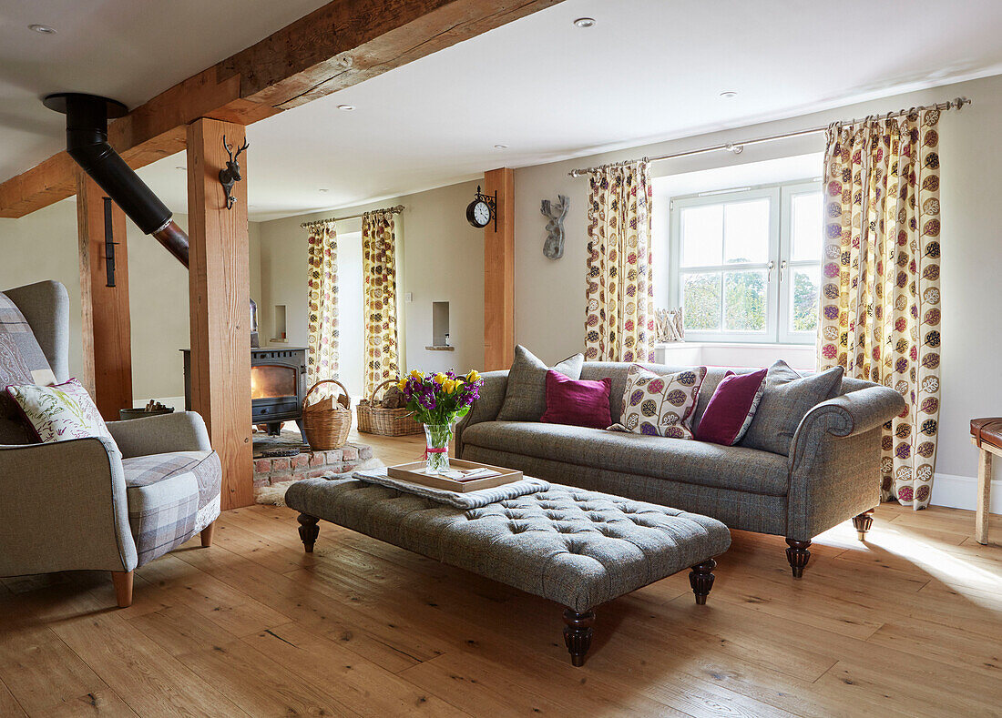 Grey ottoman and sofa in open plan Northumberland farmhouse, UK