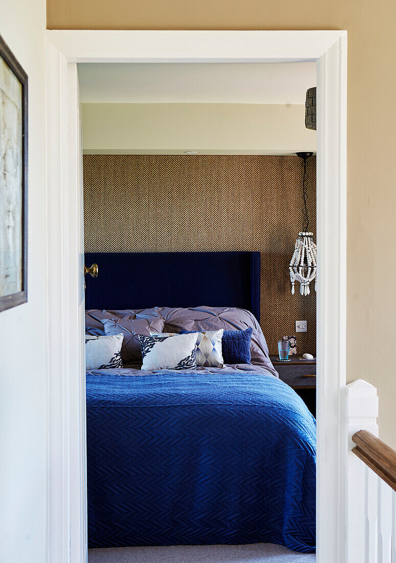 Blick durch den Türrahmen auf das blaue Doppelbett in einem Haus in Northumbria, UK