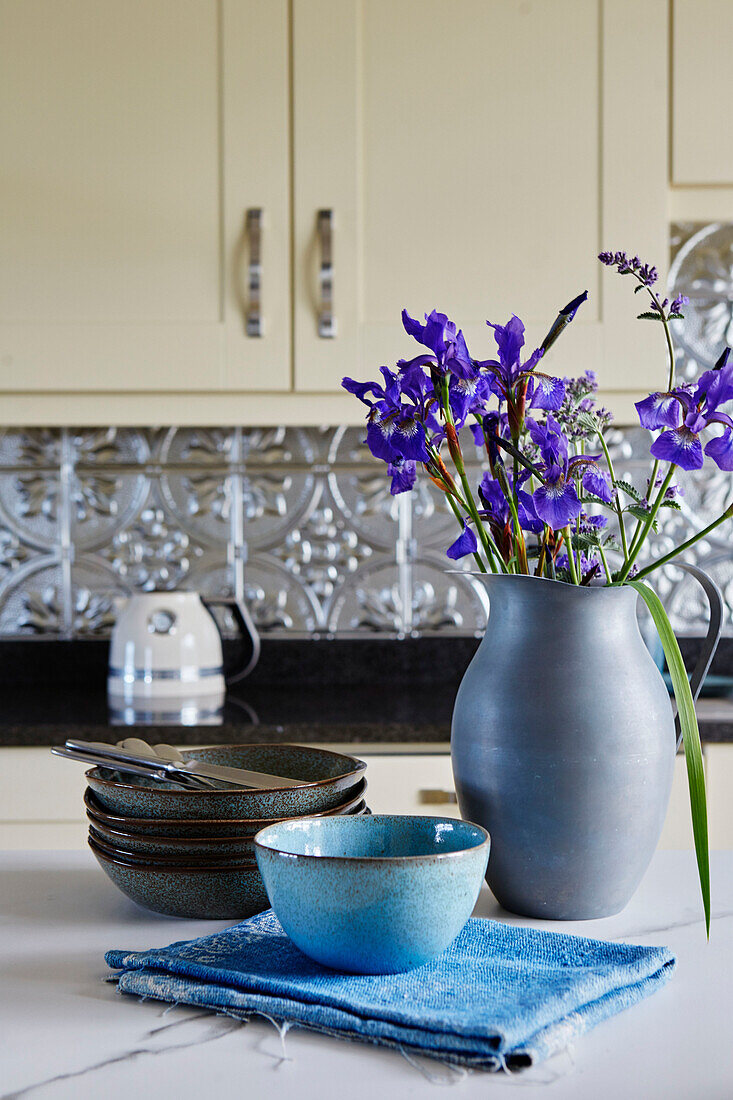 Keramikgeschirr mit blauer Kanne mit violetten Schwertlilien in einer Küche in Northumbria, UK