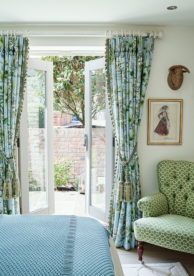 View through garden doors form Cotswolds cottage bedroom with contrasting fabrics, UK