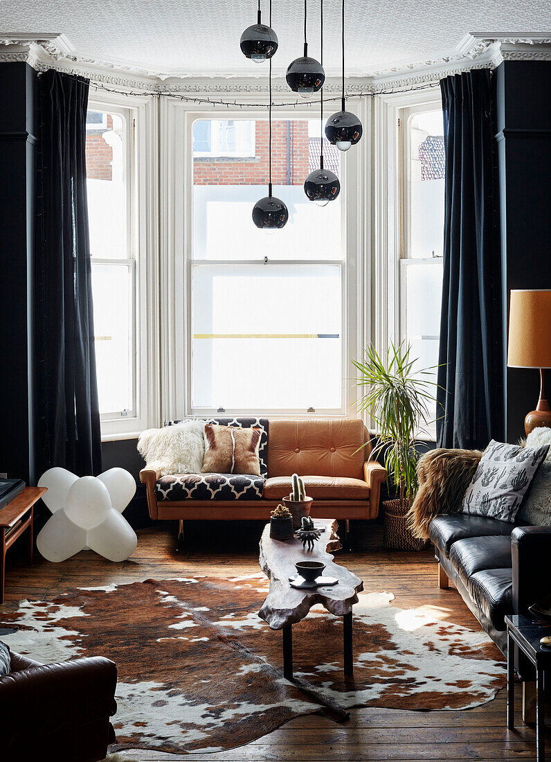 Cowhide rug and vintage leather sofas with frosted glass windows in Ramsgate living room Kent, UK