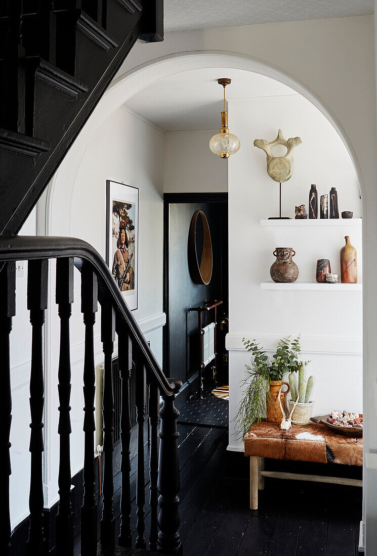 Bogengang auf dem Treppenabsatz mit schwarzem Anstrich und alten Haushaltsgegenständen in einem Haus in Ramsgate, Kent, UK