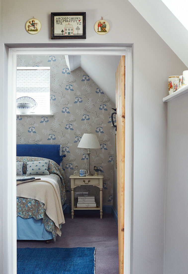 View through doorway to double bed and lamp in Cotswolds cottage, UK