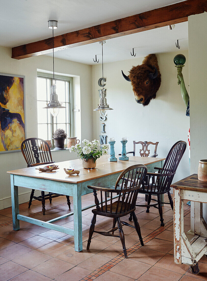 Wandmontierter Büffelkopf und Esstisch mit Stühlen in einem Haus in Devon, UK