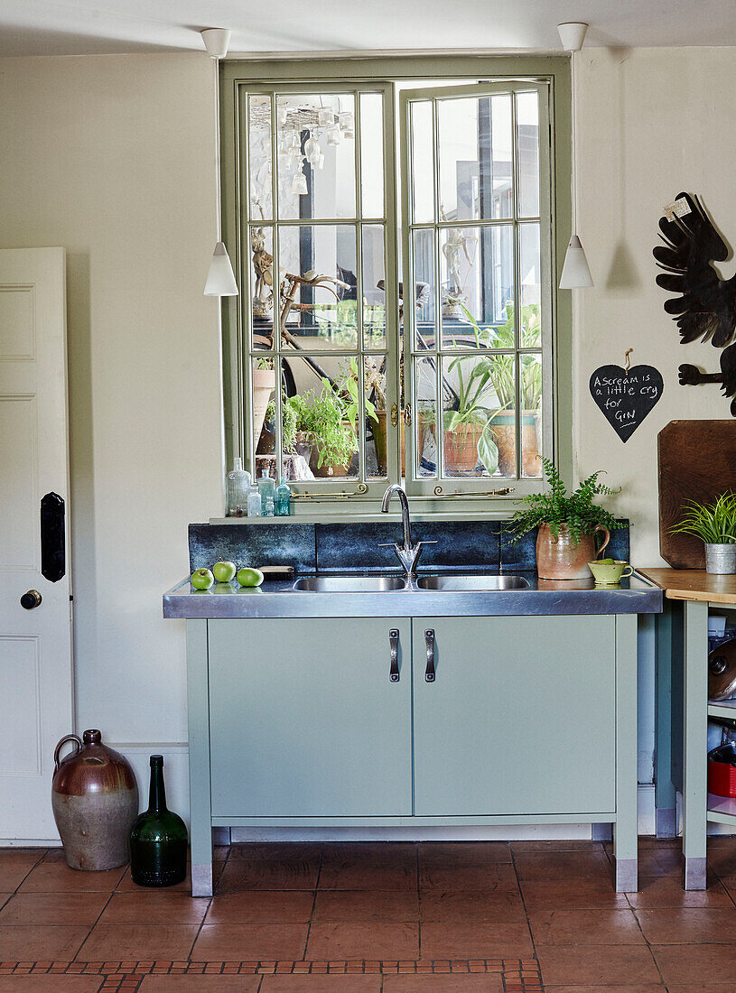 Hellblaue Edelstahlspüle am Fenster in einer Küche in Devon, UK