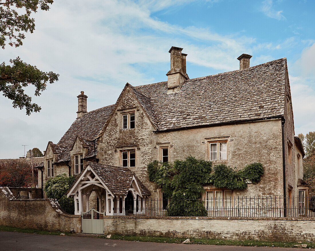 Entrance porch and tiled roof of old detached Cotswolds home, UK