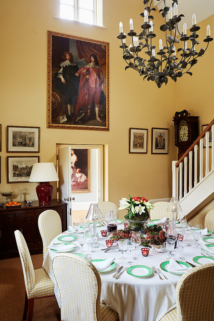 Antique chandelier above table set for Christmas dinner in double height Cotswolds home, UK