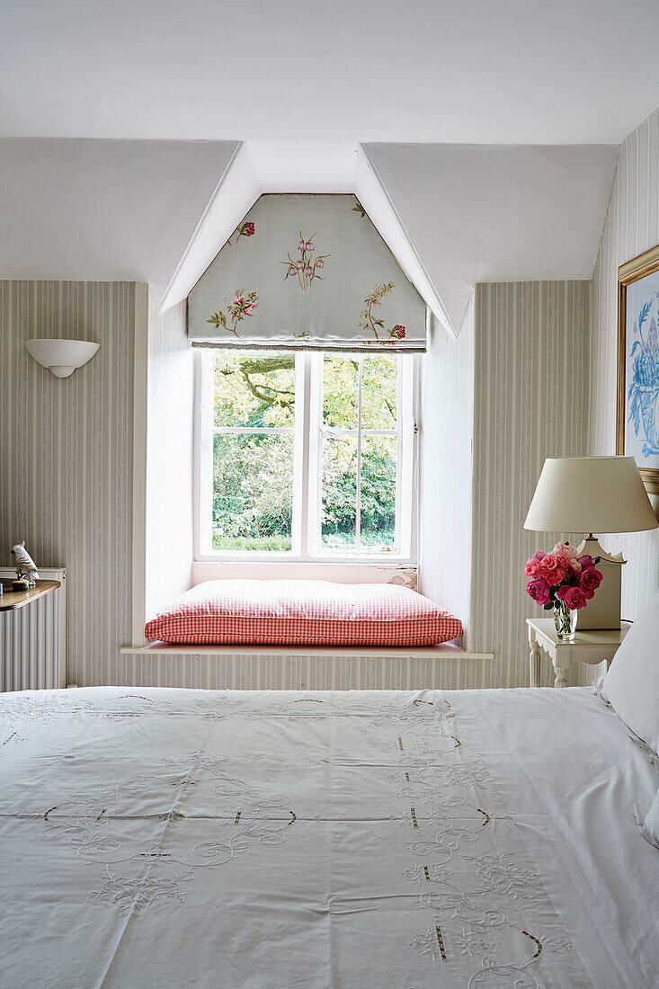 Bestickte Bettwäsche und sonnenbeschienene Fensterbank in einem Haus in den Cotswolds, UK