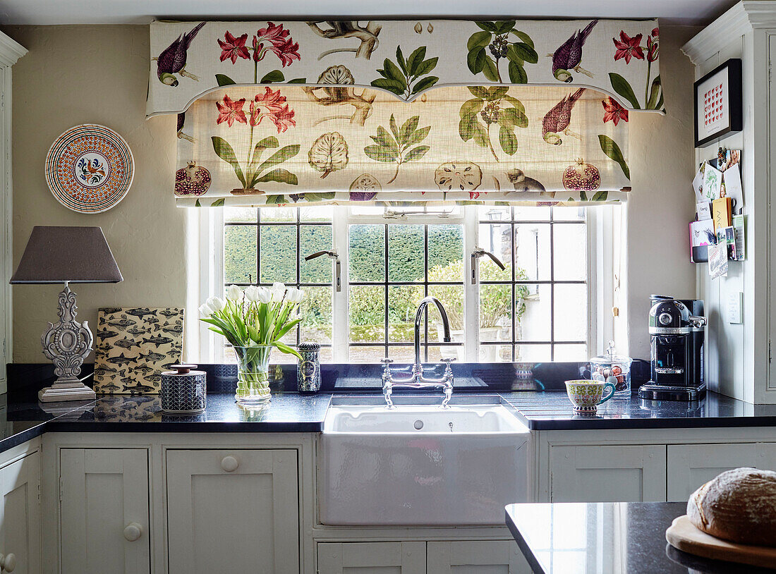 Botanische Jalousien über dem Spülbecken an einem Bleiglasfenster in einer Küche in Devon, UK