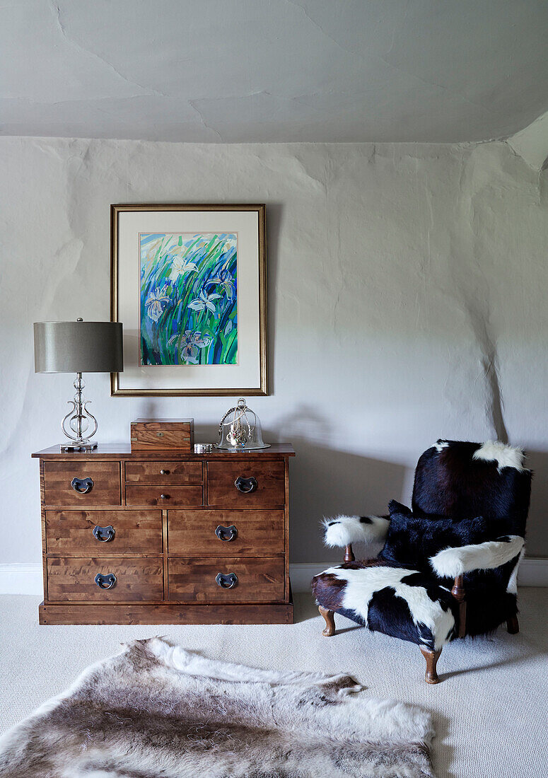 Polstersessel und Holzkommode in einem weiß getünchten Haus in Devon, UK