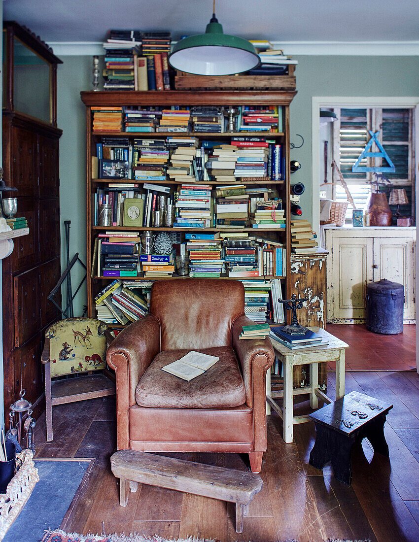 Brown leather armchair and bookcase in Somerset home, UK