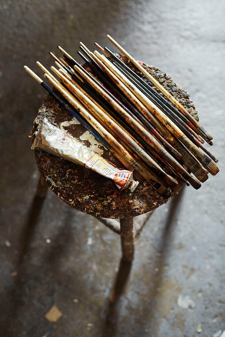 Assorted paintbrushes on stool with tube of oil paint Somerset, UK