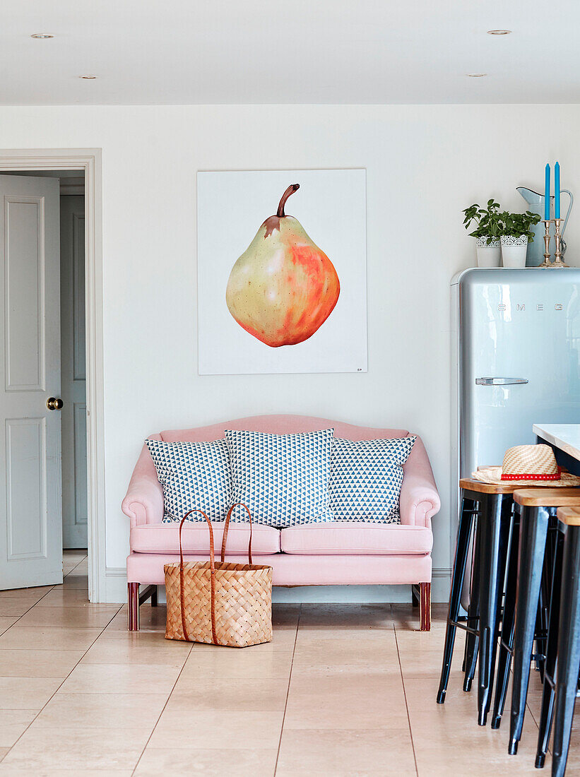 Großes Kunstwerk mit einer Birne über einem rosa Zweisitzer-Sofa in einer Küche in Oxfordshire, UK