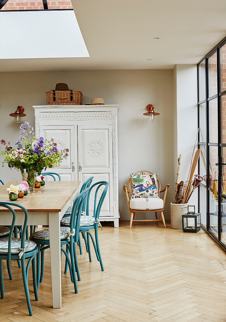 Turquoise chairs at dining table below skylight in Oxfordshire home, UK