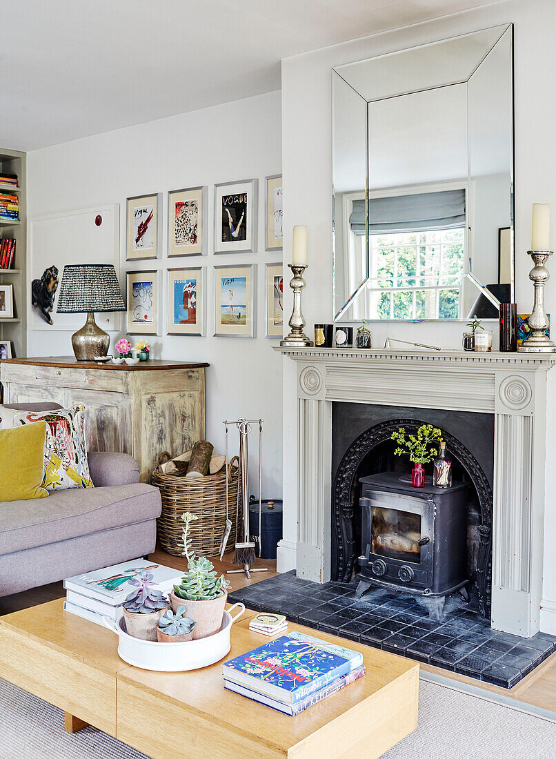 Large mirror above fireplace with wood burning stove in Oxfordshire living room, UK