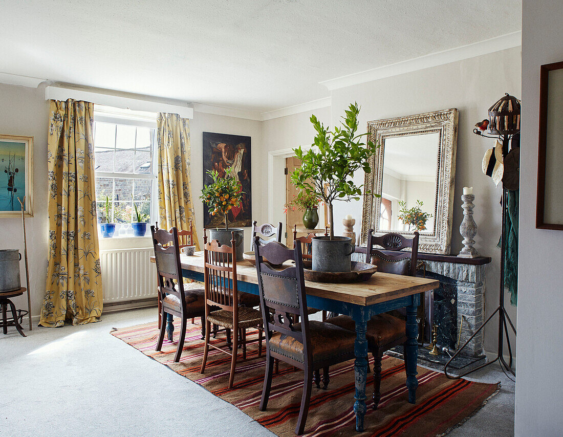 Vintage chairs at dining table with mirror on fireplace in North Yorkshire farmhouse, UK