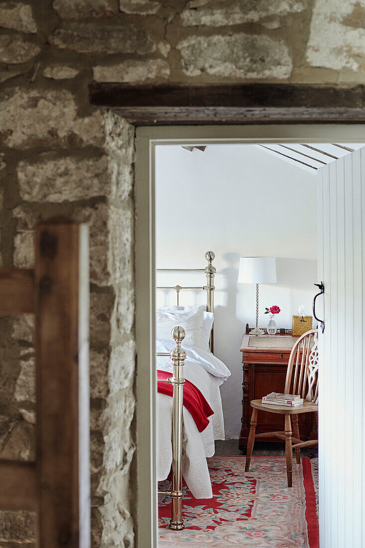 Blick durch eine offene Steintür zum Bett in einem renovierten Bauernhaus in Yorkshire, UK