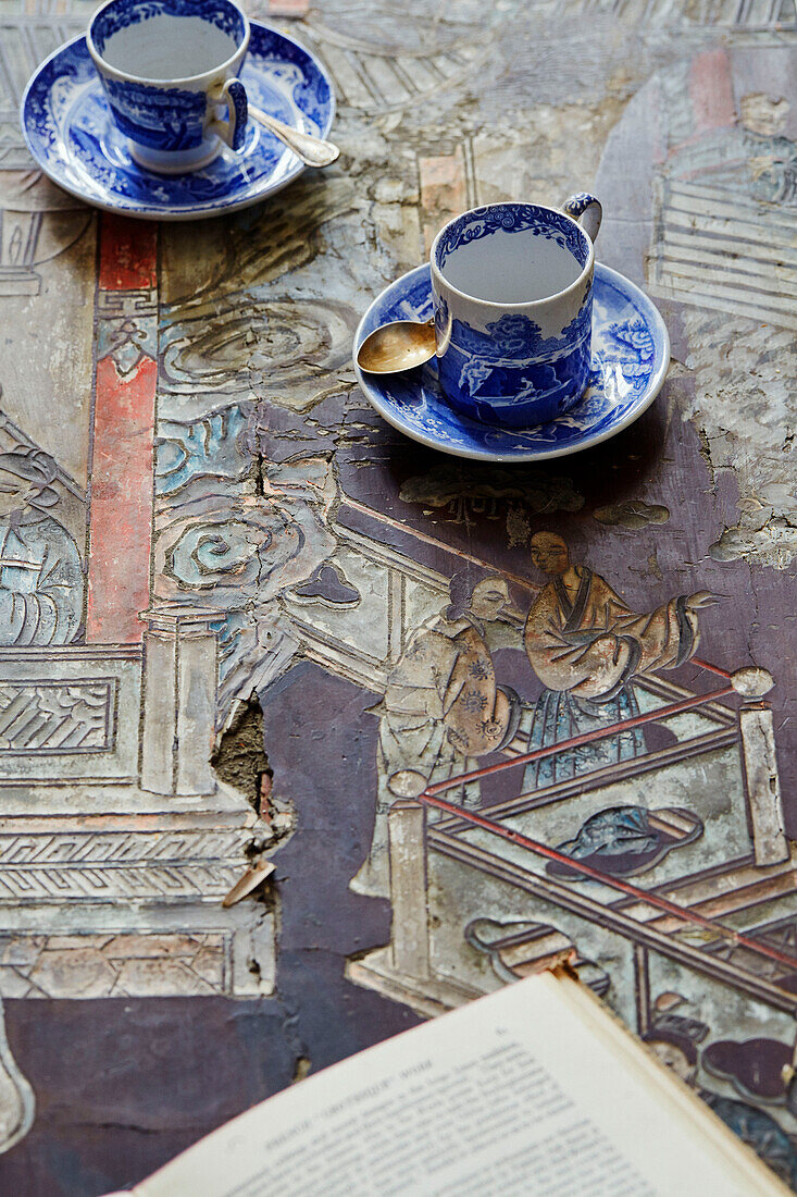 Tassen und Untertassen auf abgesplitterter orientalischer Tischplatte in Foix, Ariege, Frankreich