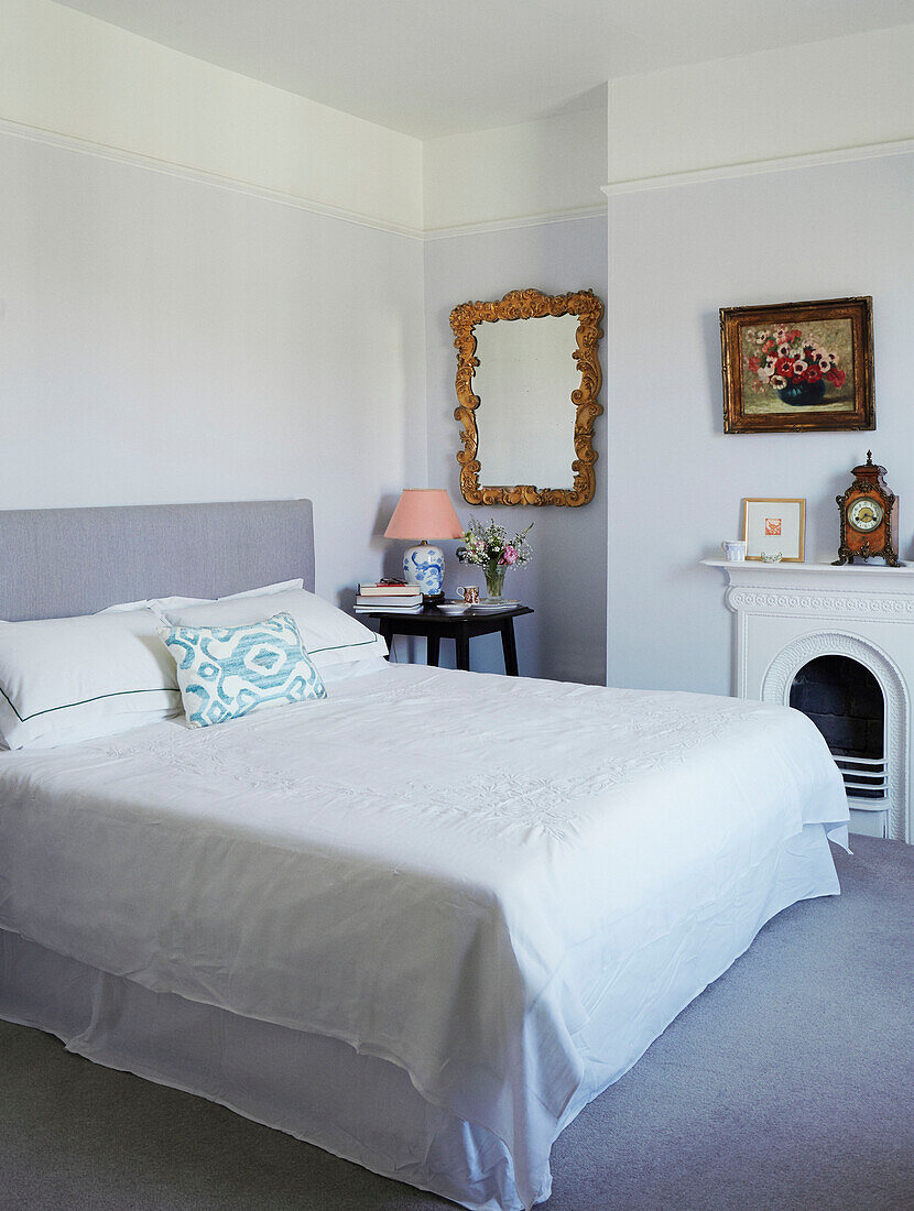 Dekorativer Spiegel und Doppelbett mit weißer, bestickter Bettwäsche in einer Wohnung im Norden, UK
