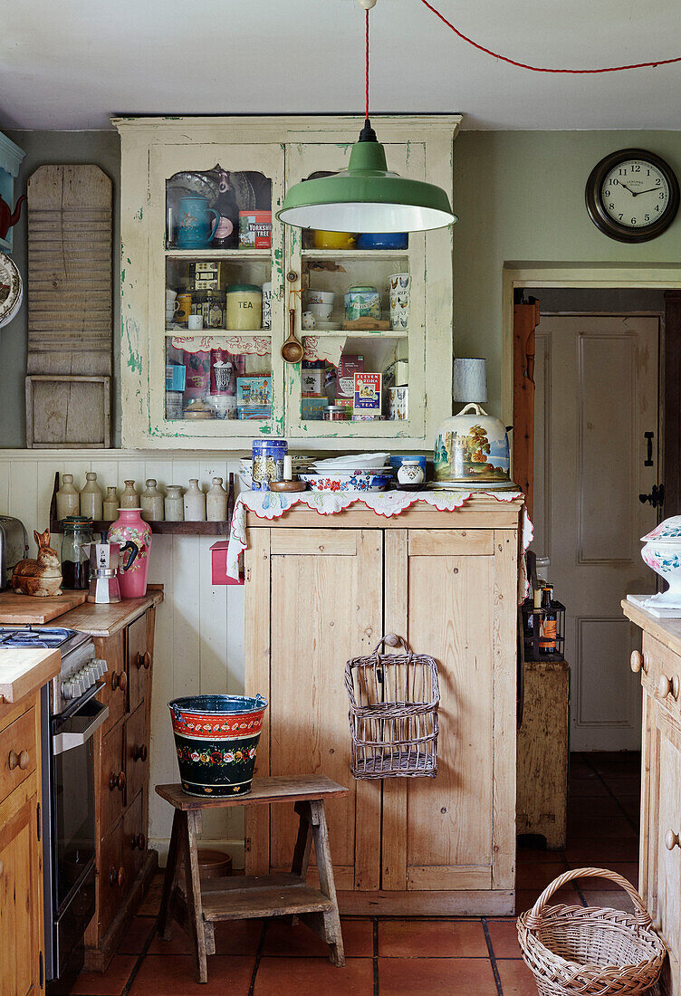 Glasvitrine und Eimer auf einem Hocker in einer kleinen Küche in Somerset, UK