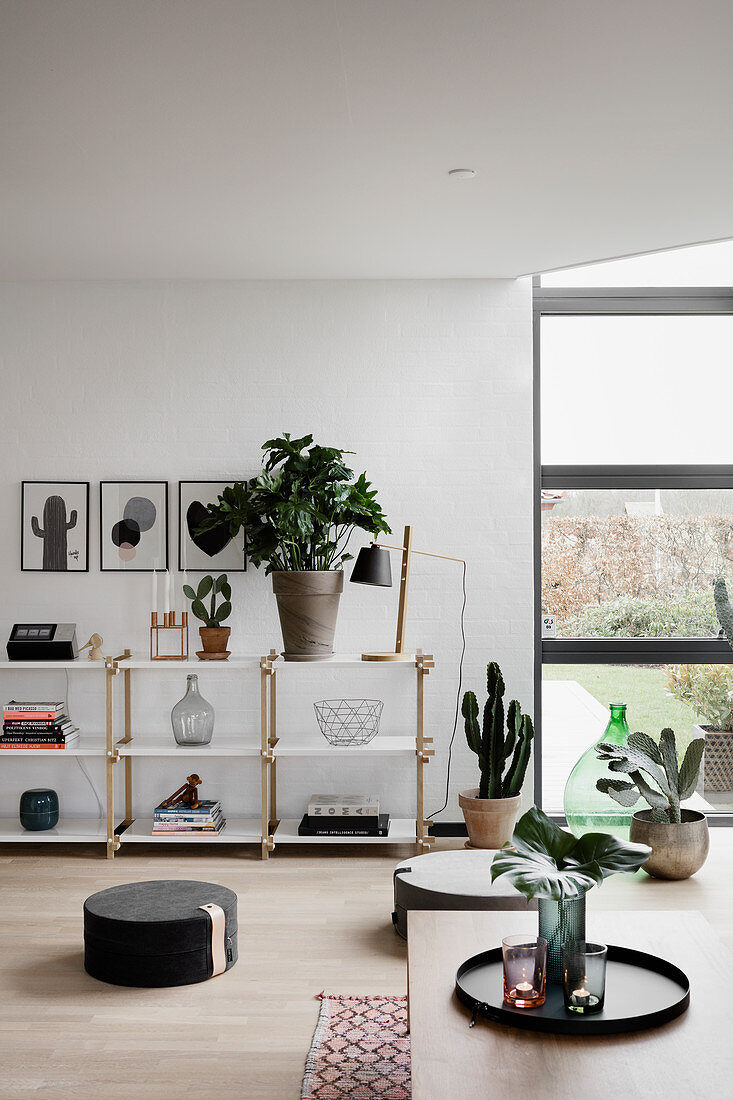Schlichtes modernes Wohnzimmer mit Pflanzen und Bodenkissen