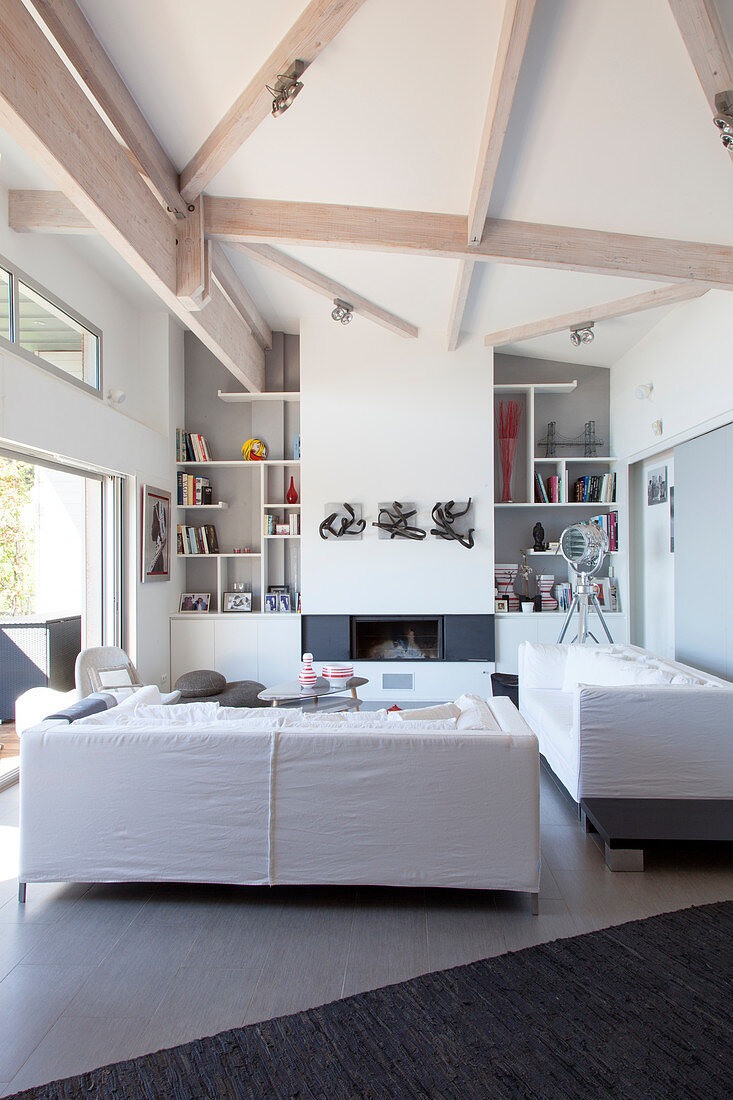 White living room with high ceiling and pale wooden beams
