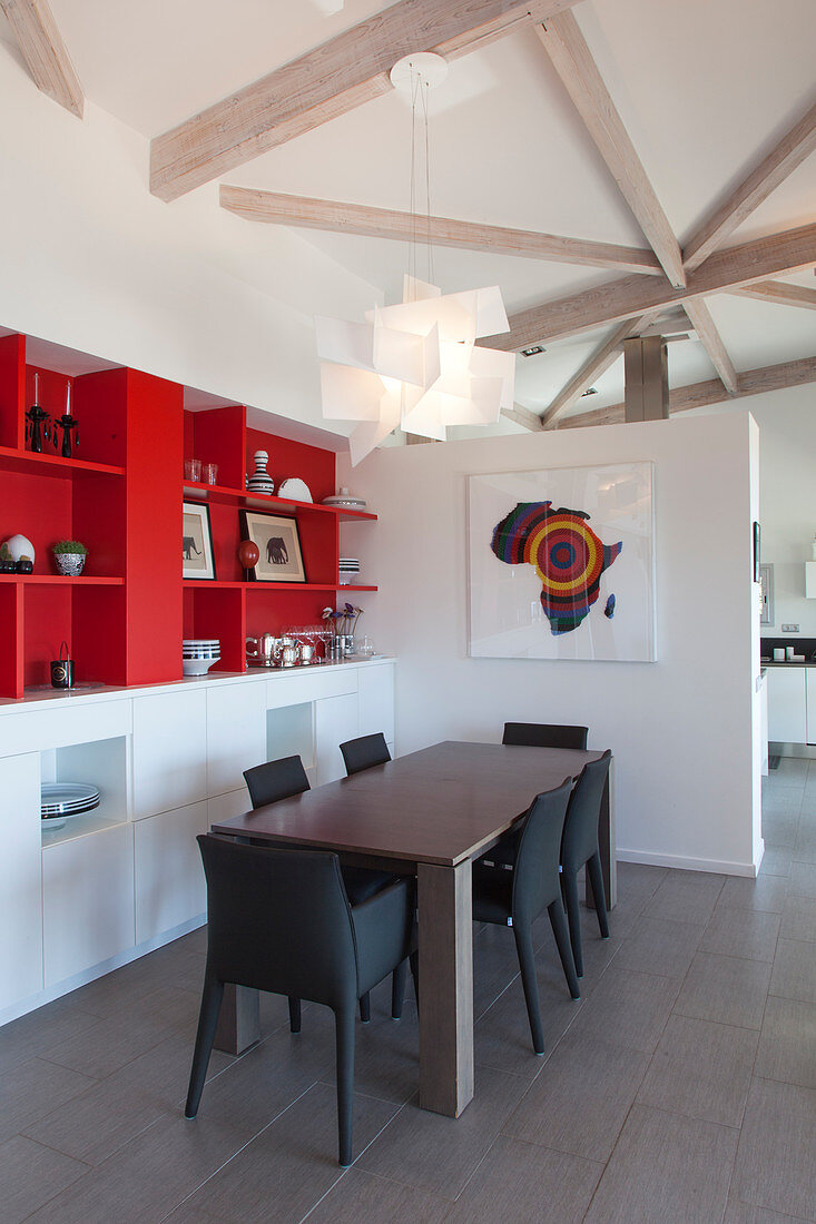 Upholstered chairs around table next to red shelves in modern dining room