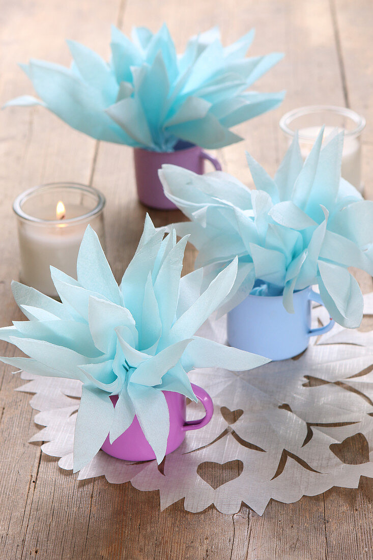Handmade table decorations made from napkin flowers in coloured enamel cups