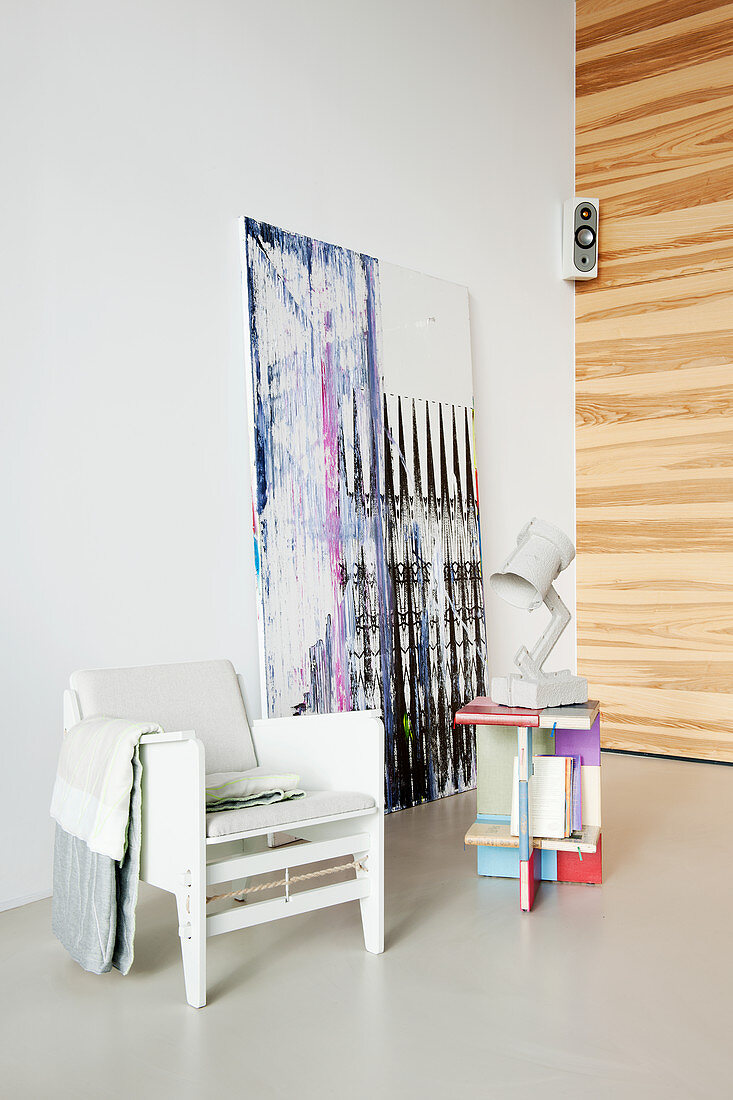 Sessel und bunter Beistelltisch vorm abstrakten Gemälde
