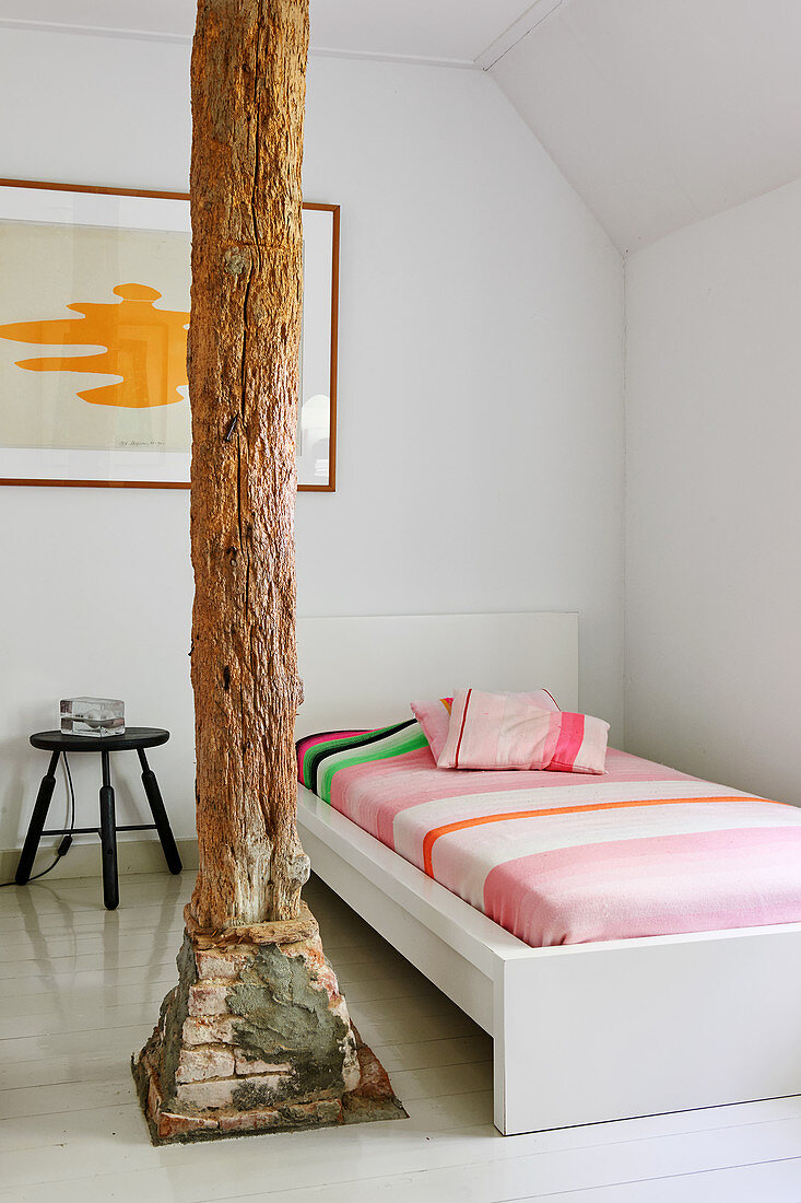 Einzelbett in weißem Zimmer mit Holzstütze