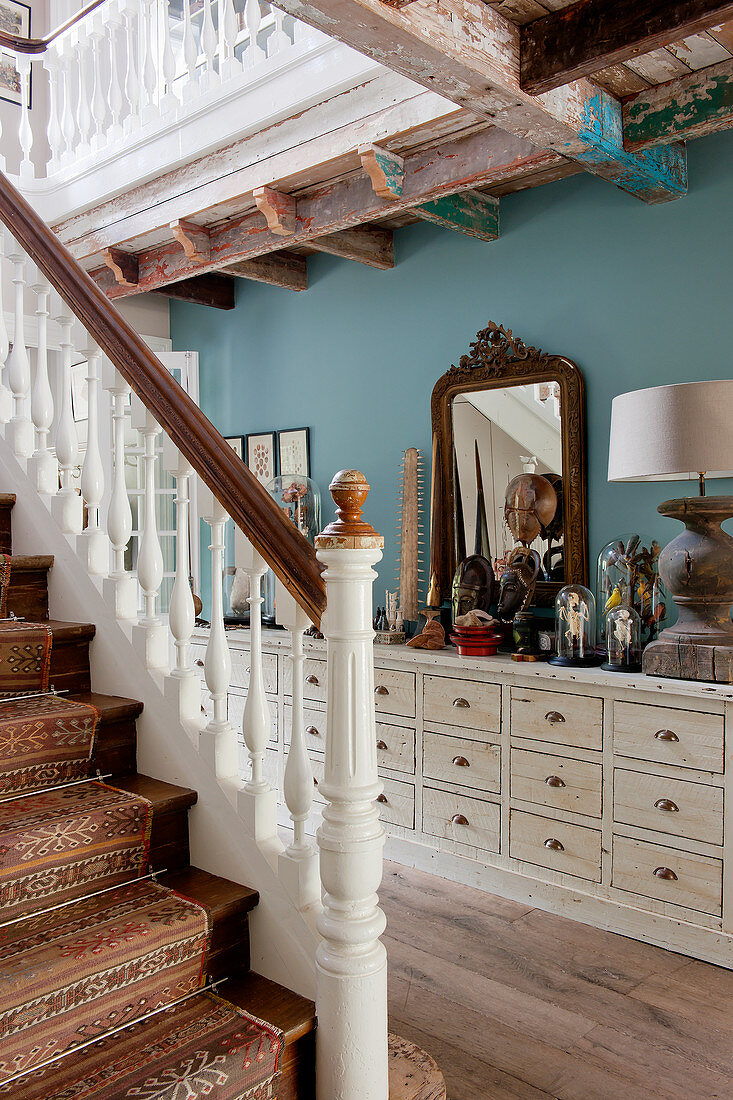 Runner with bold pattern on staircase in hallway with curiosities on sideboard