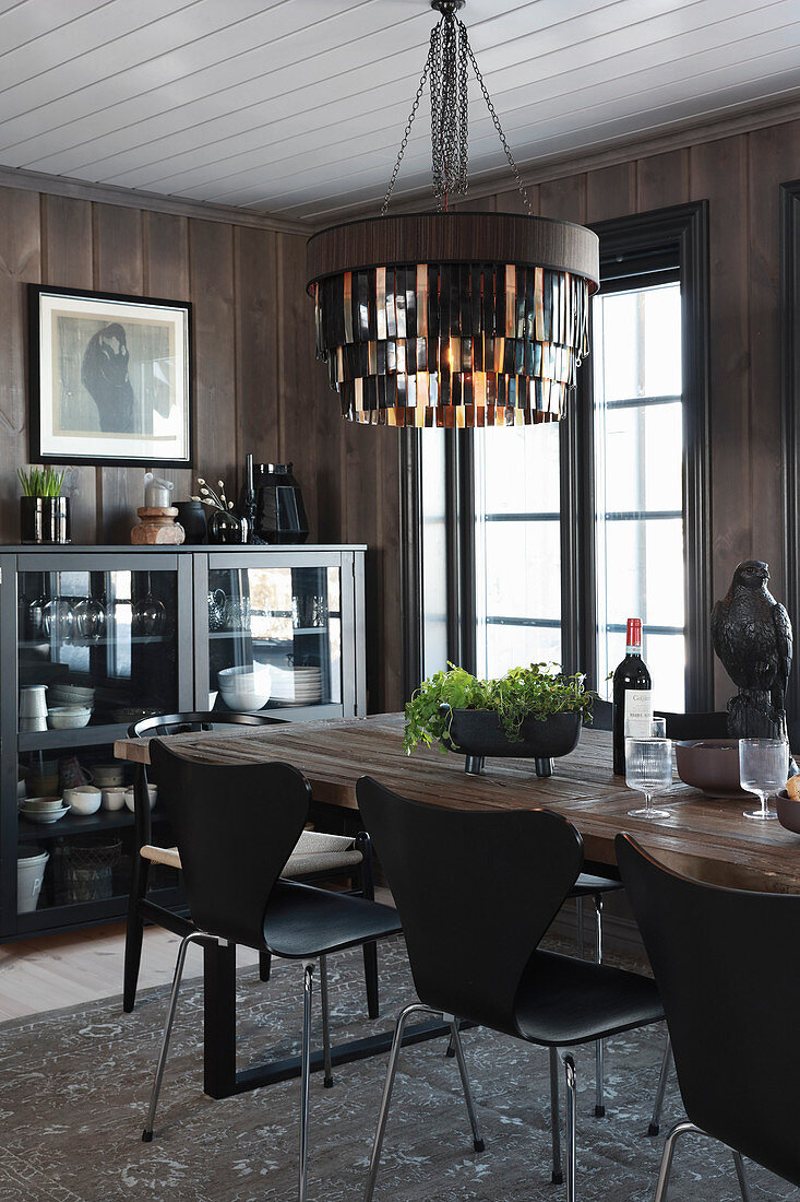 Leather-fringed lampshade above dining table and designer chairs