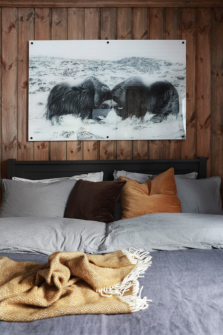 Picture of two musk oxen above bed with bed linen in earthy shades