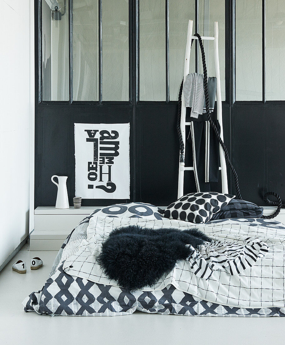 Schlafbereich mit schwarz-weißer Bettwäsche im Loft