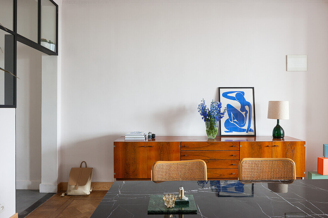 Dining area with wooden sideboard, flower vase and artwork