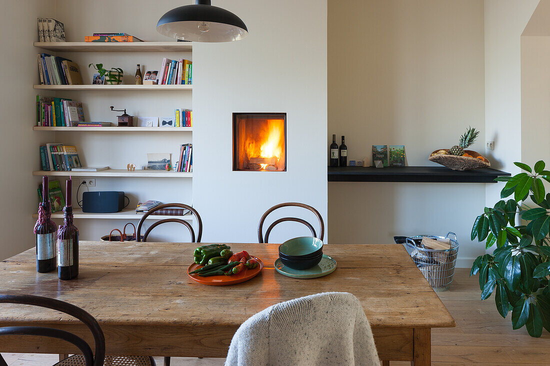 Essbereich mit Holztisch, Kamin und eingebauten Holzregalen