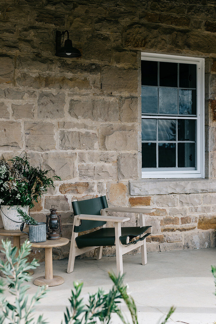 Stuhl und Beistelltisch auf der Terrasse am Haus aus Naturstein