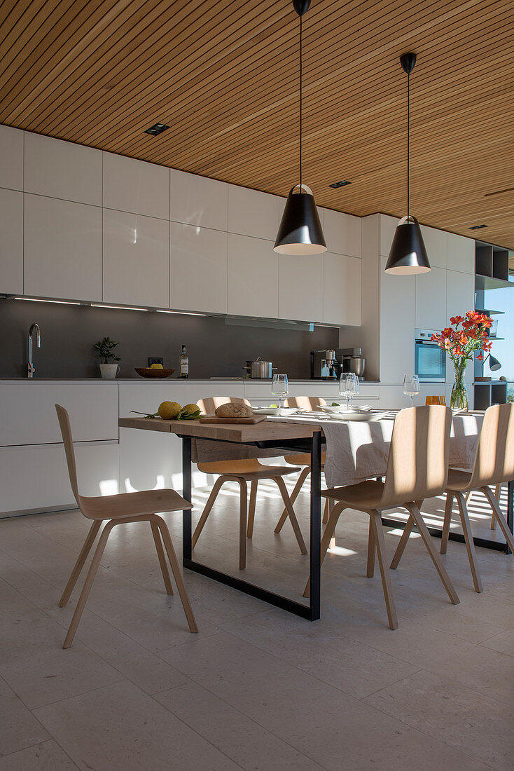 Gedeckter Esstisch vor moderner offener Küche in Weiß
