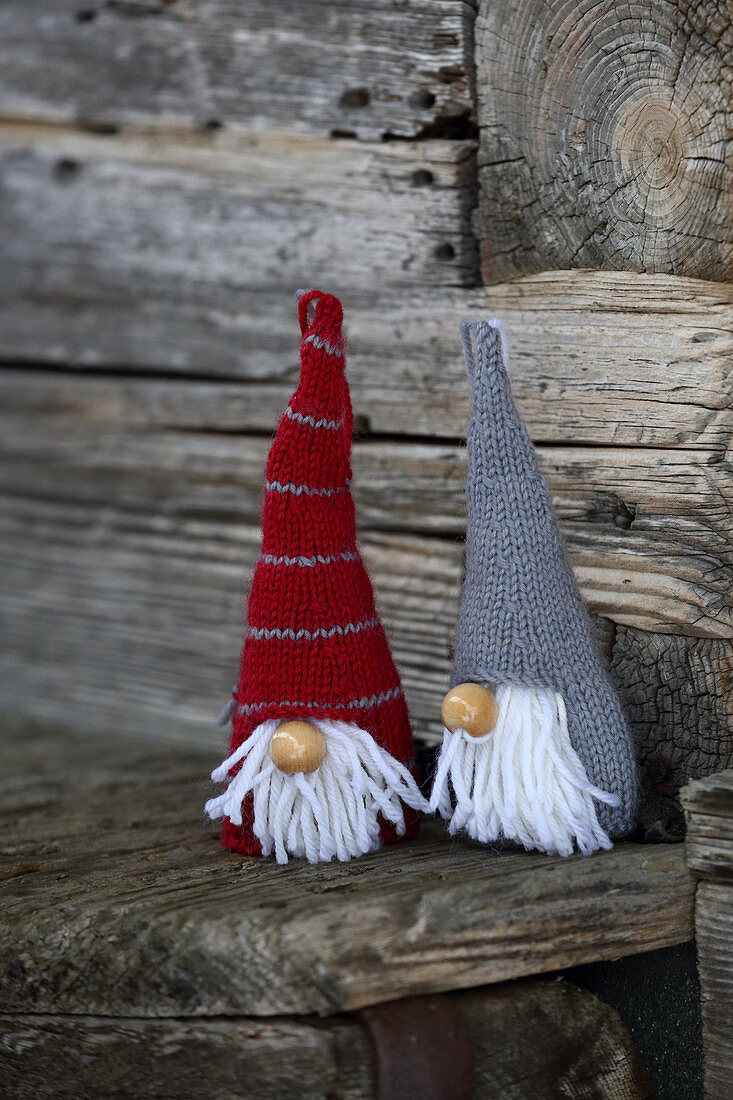 Knitted winter decorations in shapes of gnomes on rustic wood