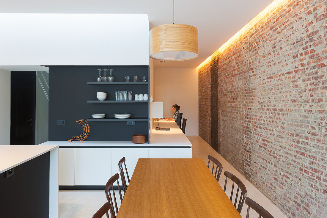 Kitchen with brick wall, wooden table, chairs and hanging pendant light