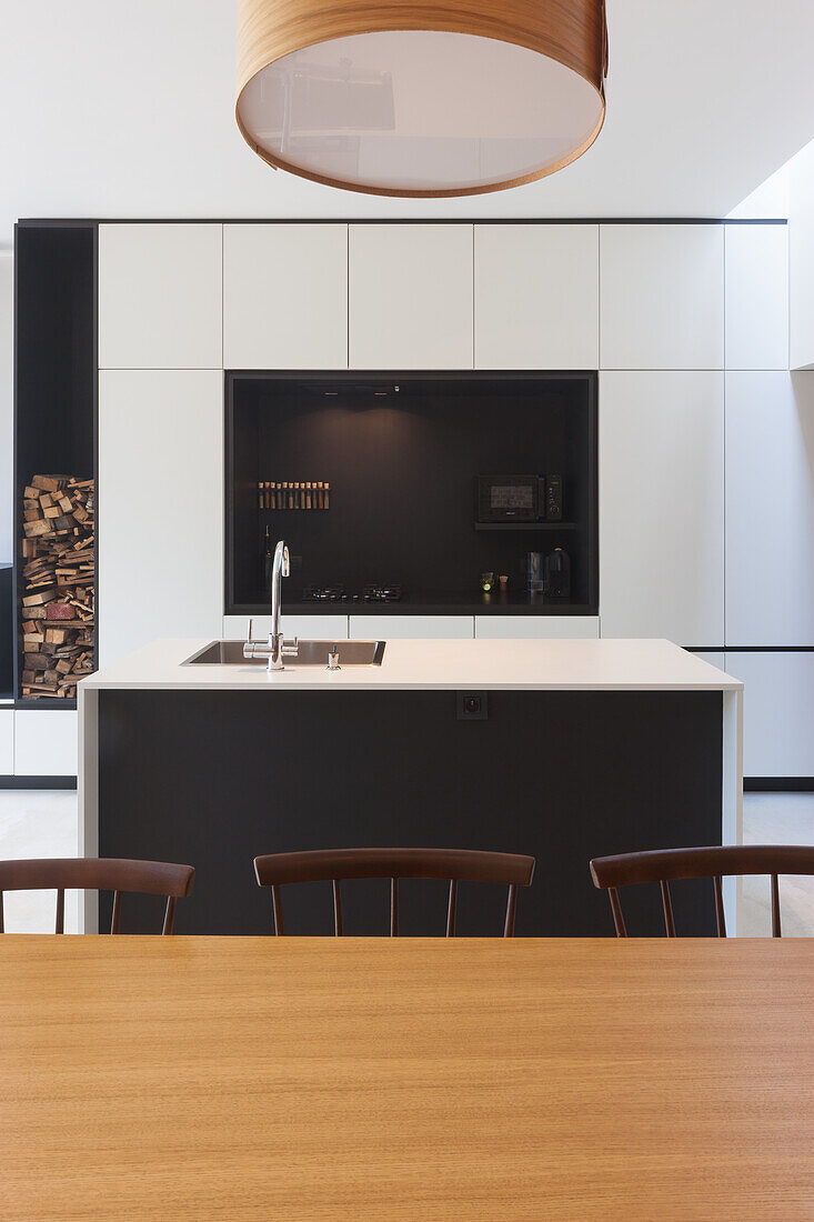 Modern kitchen with island, wooden table and integrated storage for firewood