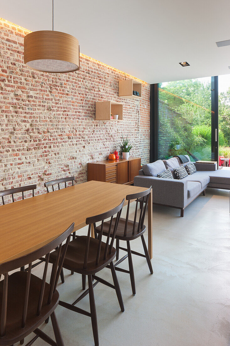 Dining area with wooden table and chairs, brick wall and adjoining living area