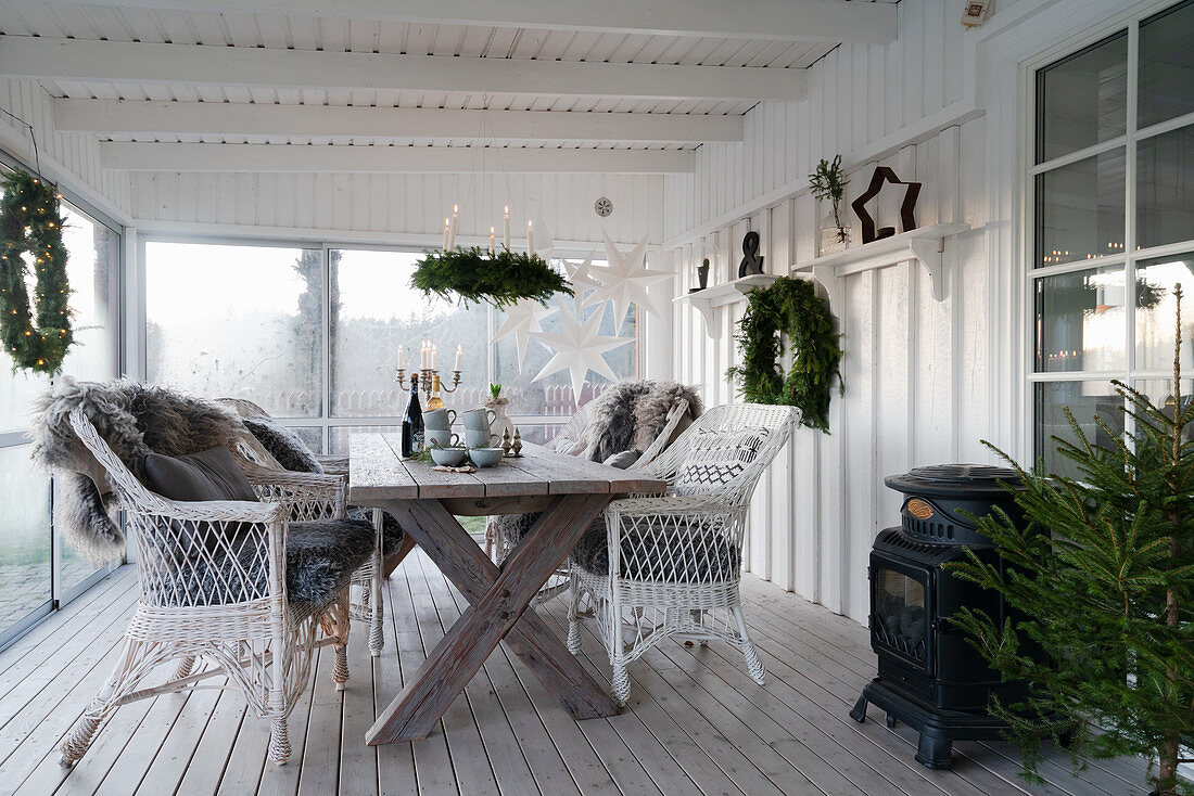 Weihnachtlich dekorierte Veranda mit Holztisch und Korbsesseln