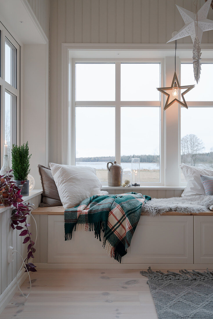 Gemütlicher Sitzplatz auf der Truhenbank am Fenster im Winter