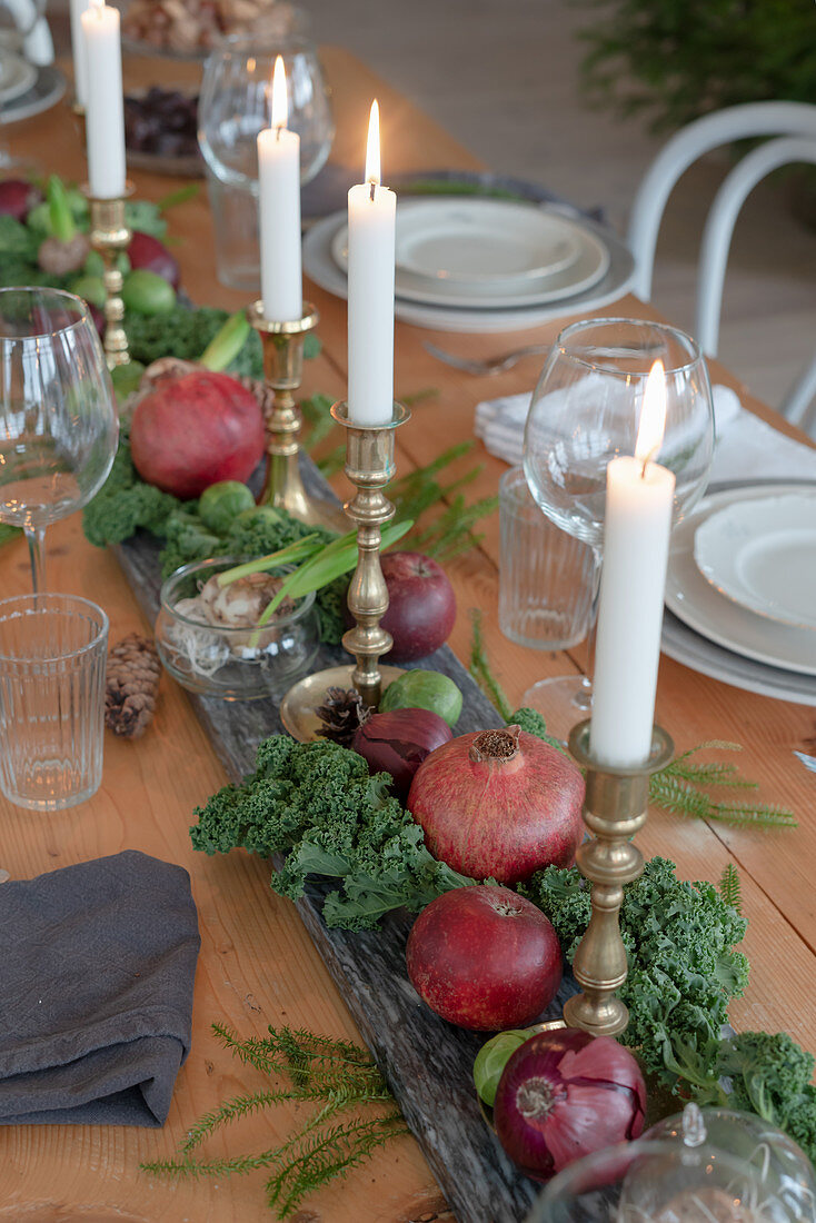 Centerpiece mit Kerzen, Granatäpfeln und Gemüse auf gedecktem Tisch